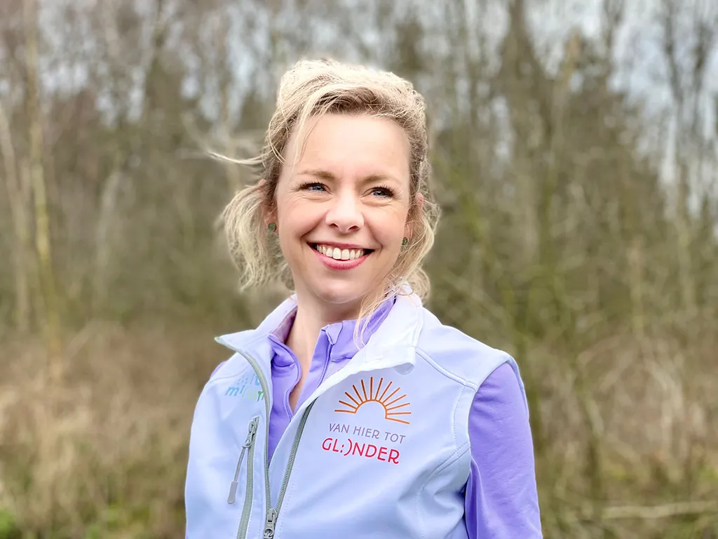 Vrouw - Linda - lachend met een jas aan met daarop Van hier tot Glunder